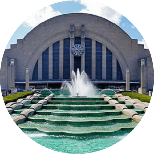 A fountain with steps leading to it and a clock in the background.