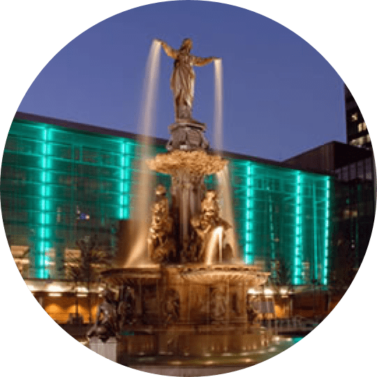 A fountain with lights and statues in the middle of it.